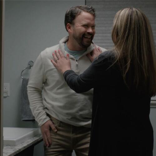 A man and woman laughing together in a bathroom