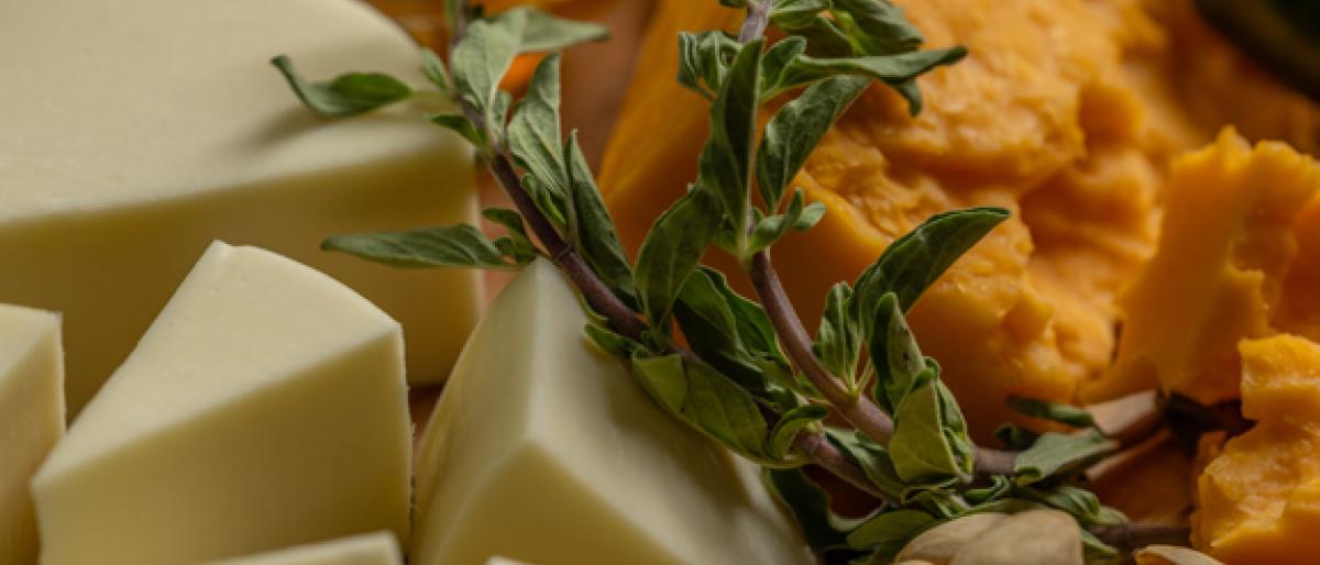 Close-up of a cheese board with honey, herbs, and pistachios