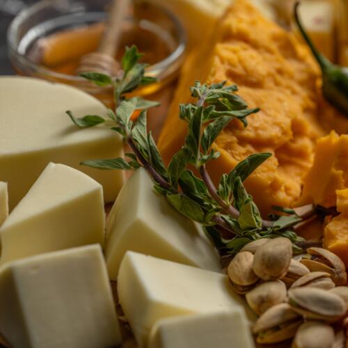 Close-up of a cheese board with honey, herbs, and pistachios
