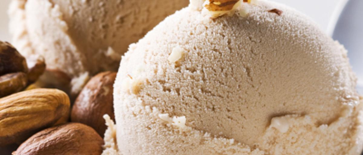 Two scoops of vanilla ice cream garnished with almonds on a white plate