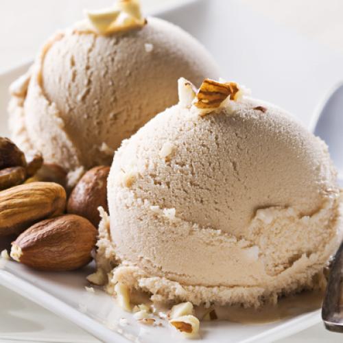 Two scoops of vanilla ice cream garnished with almonds on a white plate