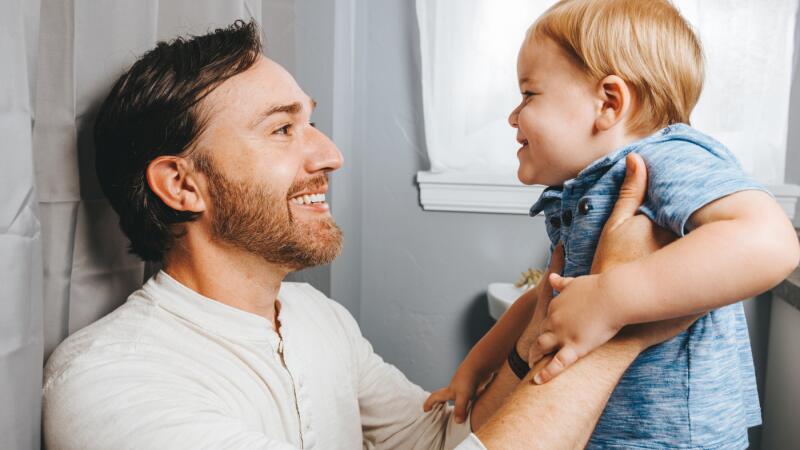Father and toddler son smiling and playing together indoors