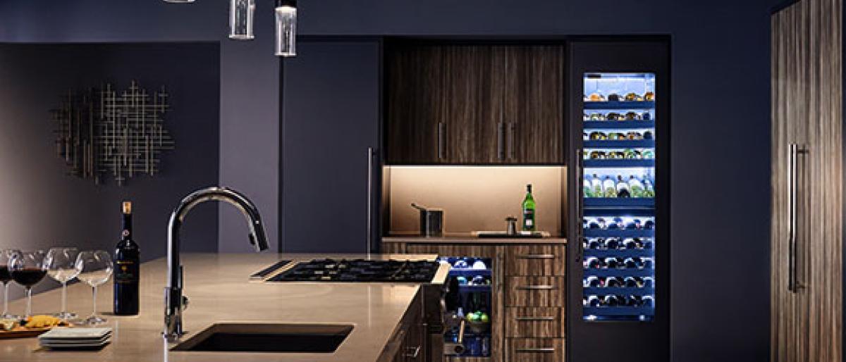 Modern kitchen with a wine display cooler, pendant lighting, and a wine bottle on the island