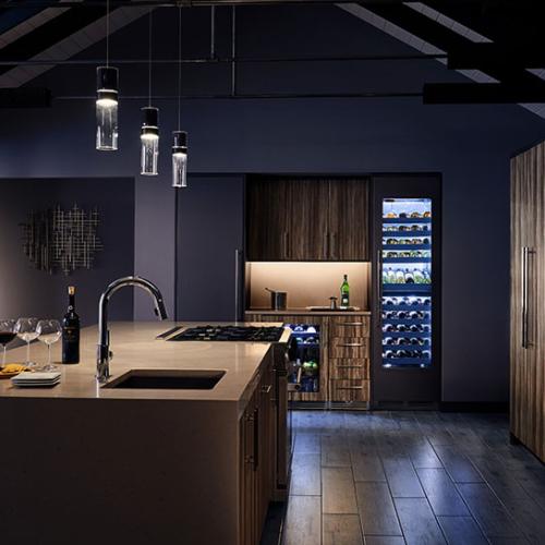 Modern kitchen with a wine display cooler, pendant lighting, and a wine bottle on the island