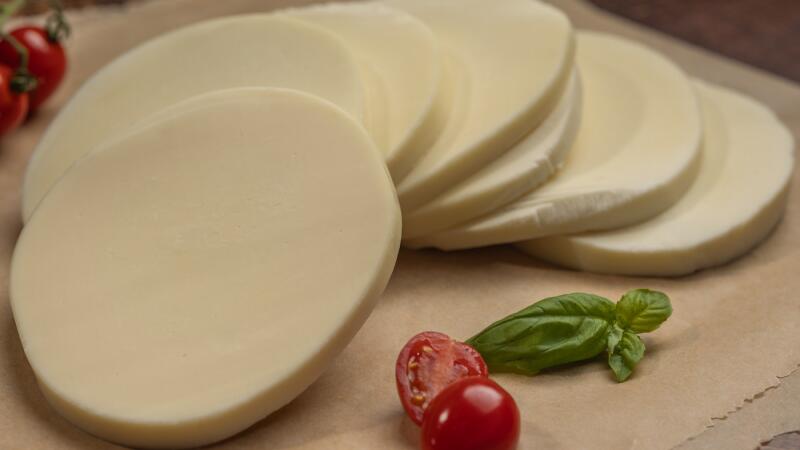 Sliced provolone cheese with cherry tomatoes and a basil sprig