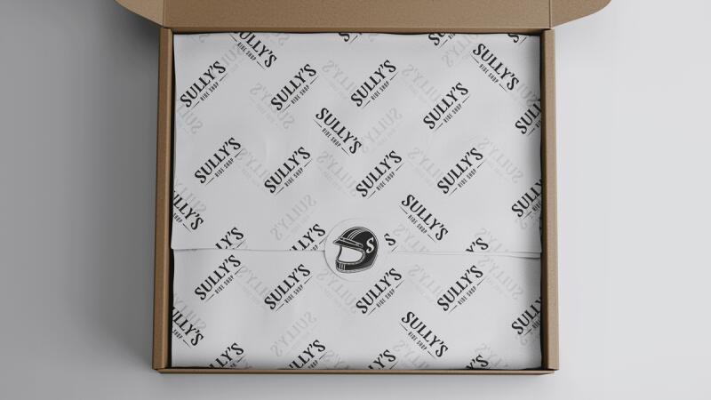 Open shipping box with Sully's Ride Shop branded tissue paper and a helmet logo seal