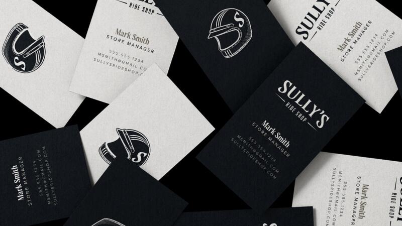 Mockup of Sully's Ride Shop business cards with a helmet logo