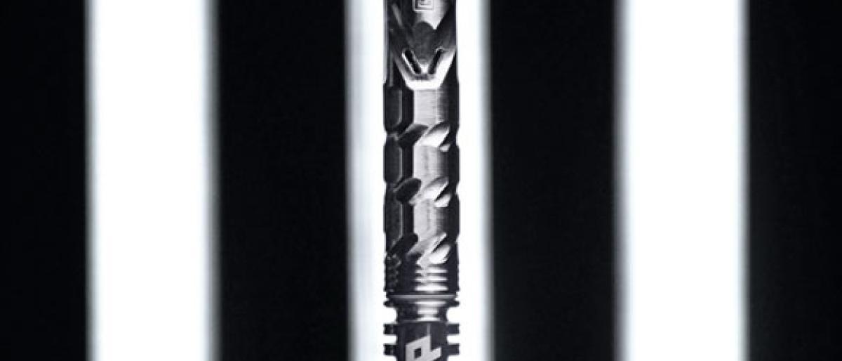 A DynaVap vaporizer pen with a hexagonal textured grip standing against a striped light background
