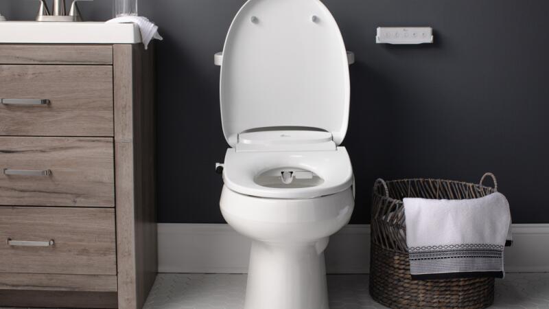 Bathroom with an open-lid smart bidet toilet seat and a wall-mounted control panel