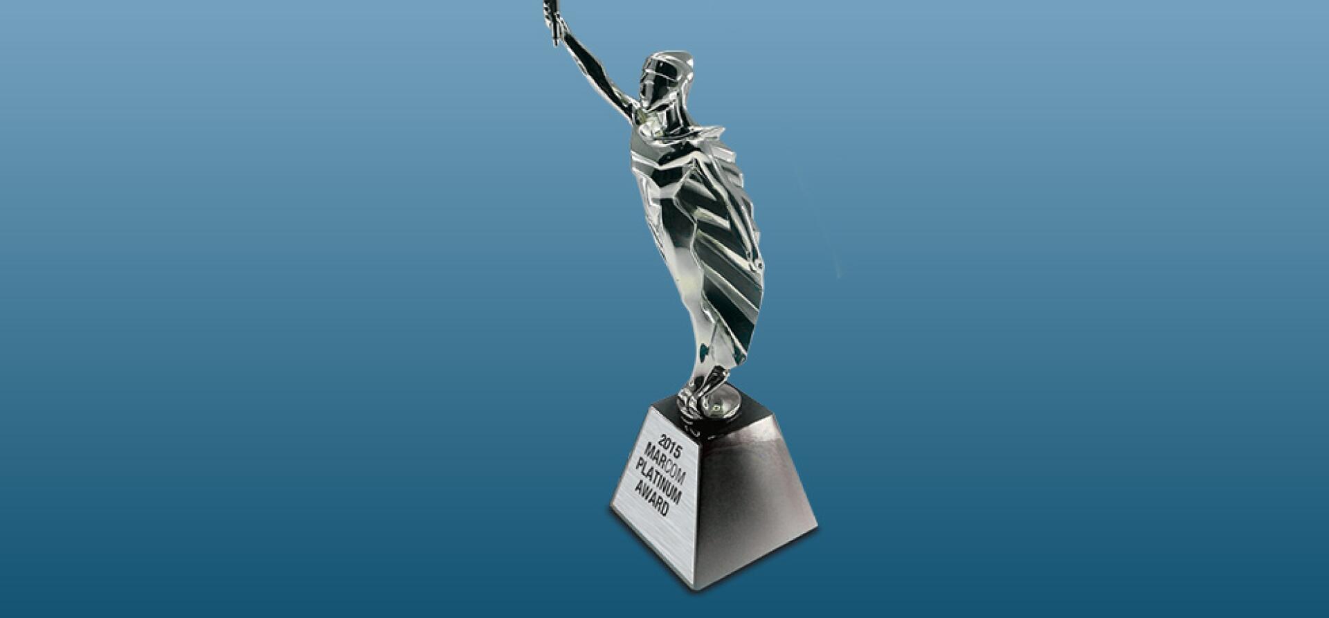 Silver trophy award on a stand, engraved with a 2015 MarCom Platinum Award label