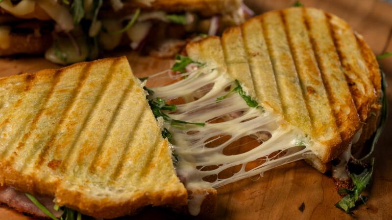 Grilled panini sandwich cut in half showing a melted cheese pull