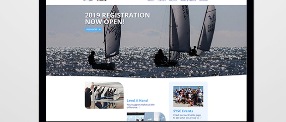 Laptop showing the Sheboygan Youth Sailing Center website with a sailboat racing photo