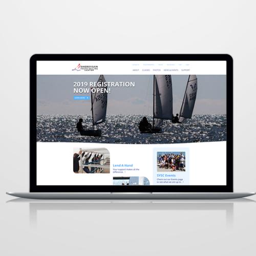 Laptop showing the Sheboygan Youth Sailing Center website with a sailboat racing photo